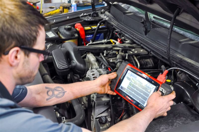 Auto repair technician at Corey's Car Care Center in Fargo, ND running a professional diagnostic scan under the hood